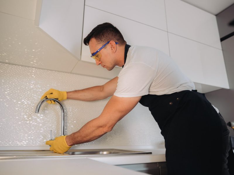 maintenance-man-installing-plumbing-equipment-in-the-kitchen.jpg